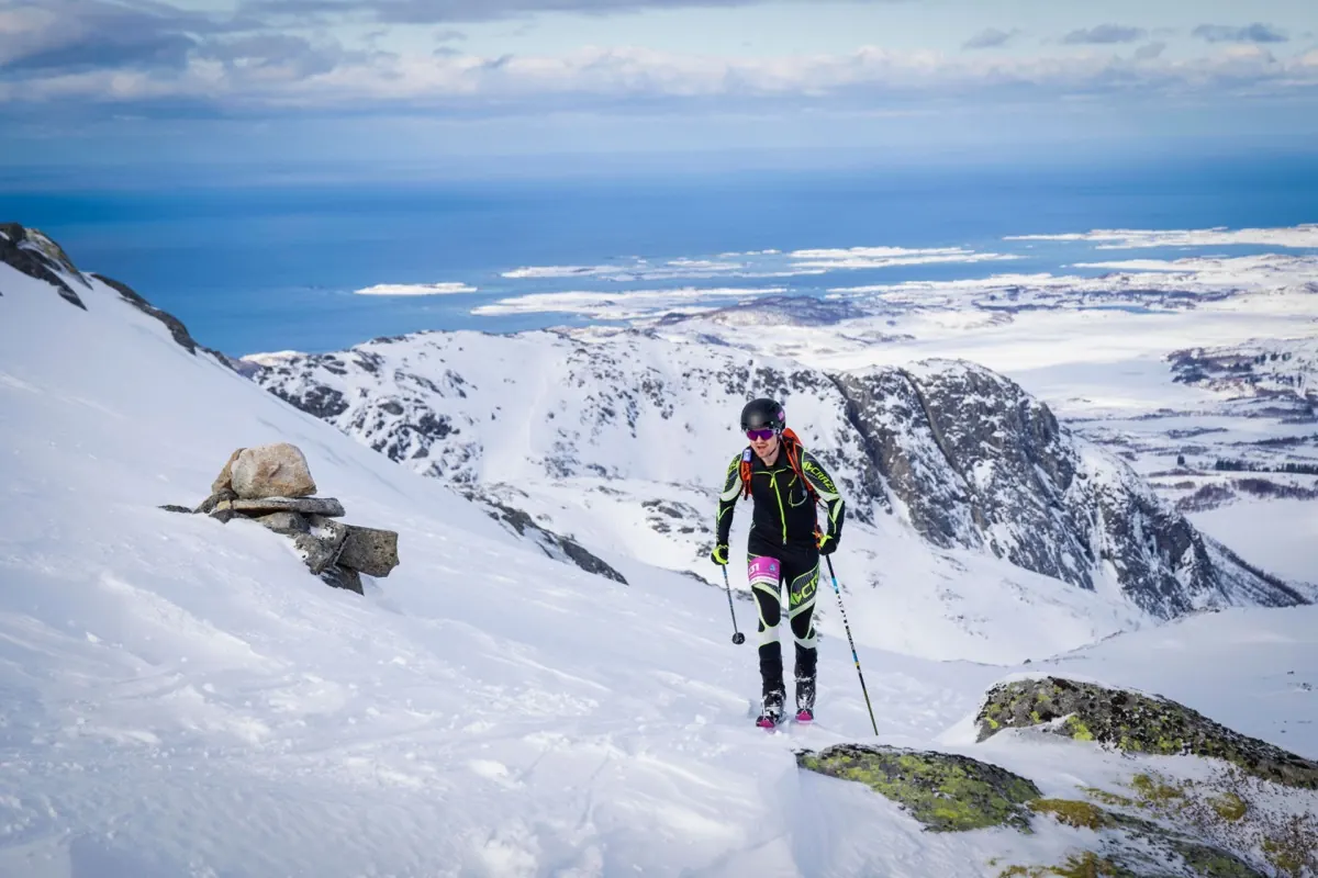 Ski mountaineer skinning up a ridge above the sea in Lofoten
